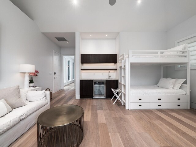 bedroom featuring a sink, beverage cooler, light wood-style flooring, recessed lighting, and visible vents