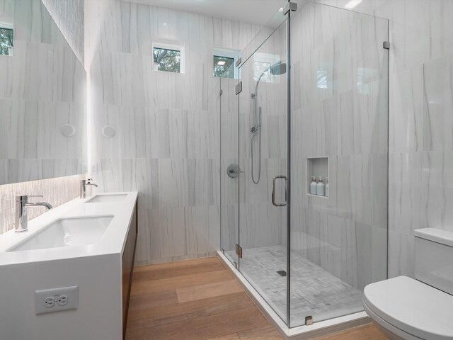 full bath featuring a sink, a stall shower, toilet, and tile walls