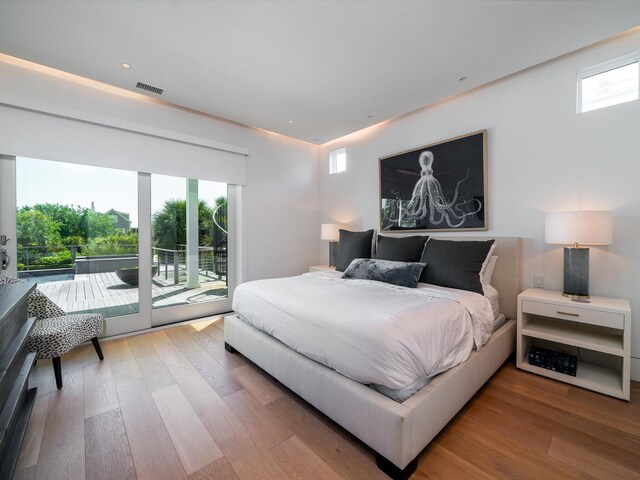 bedroom with access to outside, visible vents, and wood finished floors