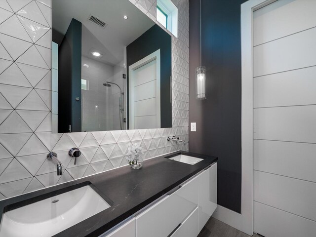 bathroom featuring visible vents, a sink, backsplash, and a stall shower