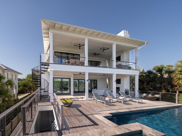 back of property with ceiling fan, a fenced in pool, stairs, and a balcony