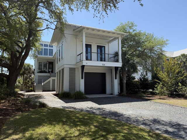 view of front of property featuring stairway, an attached garage, driveway, and a balcony