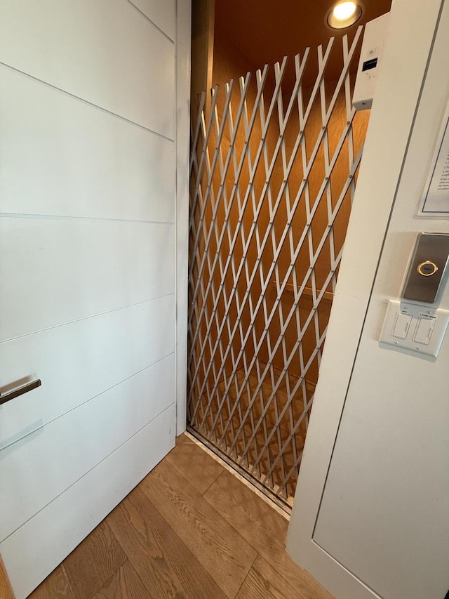 interior details featuring a gate, elevator, and wood finished floors