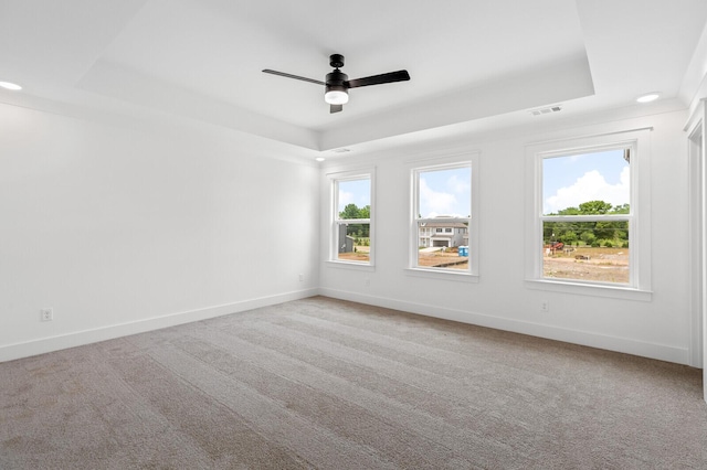 carpeted spare room with ceiling fan and a tray ceiling