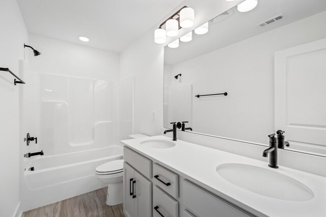 full bathroom with hardwood / wood-style floors, vanity, toilet, and shower / tub combination