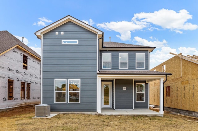 rear view of property with central AC unit, a patio area, and a lawn