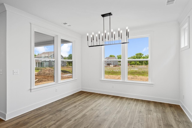 unfurnished dining area with hardwood / wood-style floors and a notable chandelier