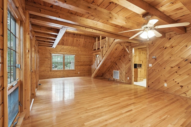 additional living space with beam ceiling, light wood-type flooring, and wood walls