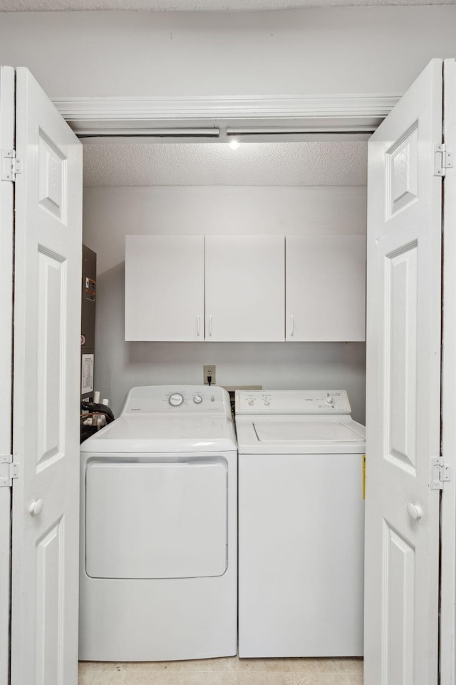 washroom with washer and clothes dryer, cabinets, and a textured ceiling