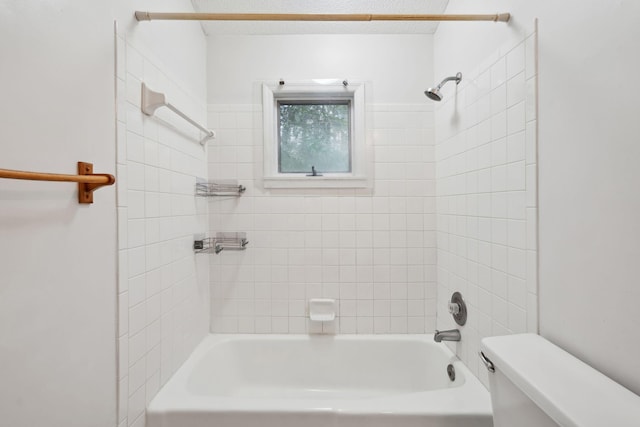 bathroom with tiled shower / bath, a textured ceiling, and toilet