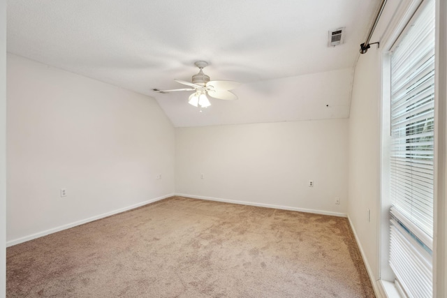 carpeted spare room featuring vaulted ceiling and ceiling fan