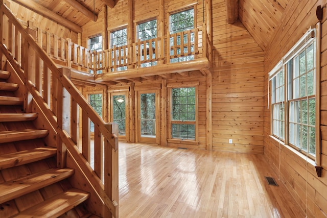 unfurnished living room with hardwood / wood-style floors, high vaulted ceiling, wooden walls, wooden ceiling, and beam ceiling