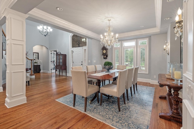 dining space with arched walkways, a chandelier, stairs, light wood-style flooring, and baseboards
