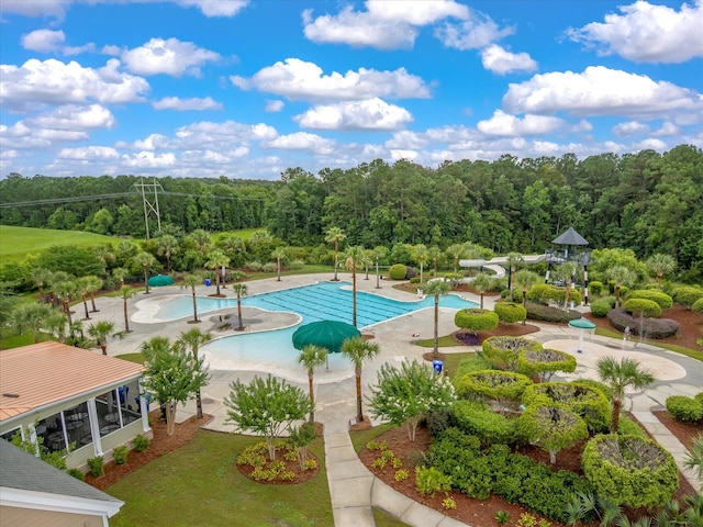 community pool with a patio and a forest view