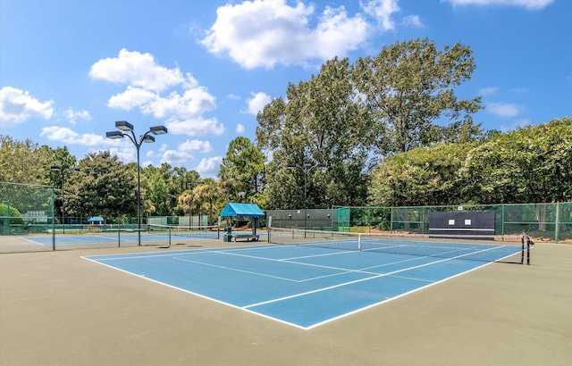 view of tennis court featuring community basketball court and fence