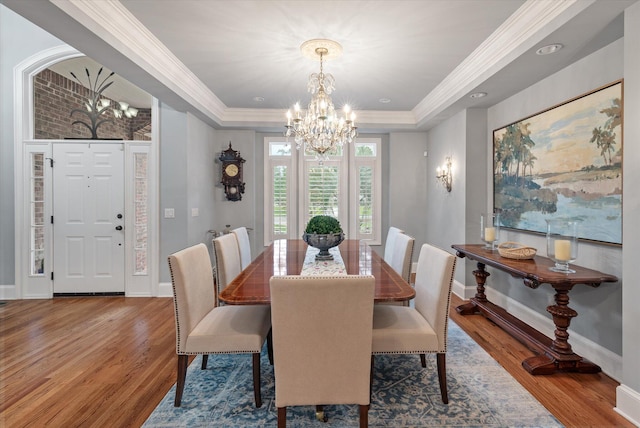 dining room featuring a chandelier, wood finished floors, baseboards, crown molding, and a tray ceiling