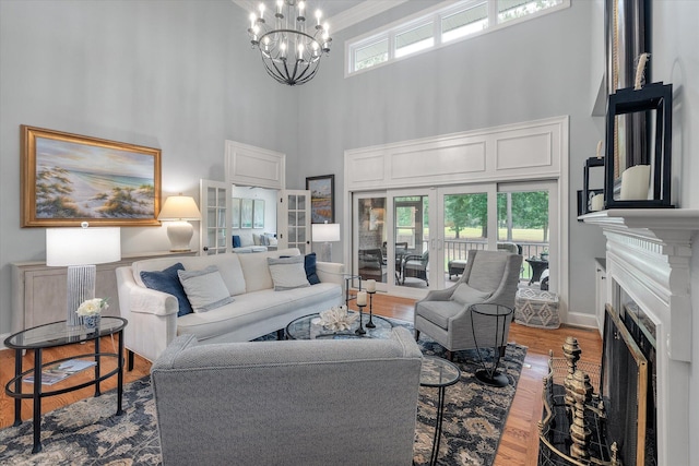 living room featuring a high ceiling, a chandelier, a fireplace, wood finished floors, and baseboards