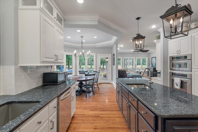 kitchen featuring a chandelier, a sink, stainless steel appliances, light wood-style flooring, and white cabinets
