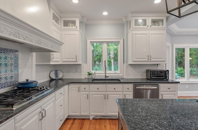 kitchen featuring a sink, stainless steel appliances, custom exhaust hood, white cabinetry, and dark stone counters