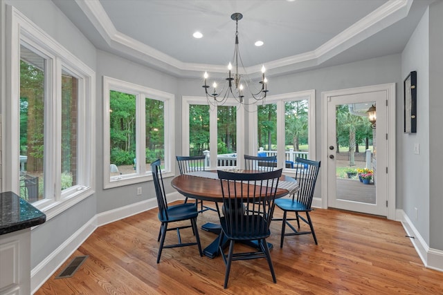 dining room featuring a chandelier, ornamental molding, light wood-style floors, baseboards, and a tray ceiling
