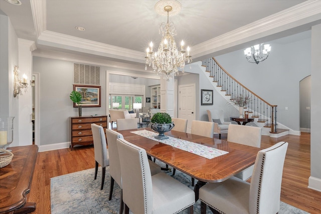 dining room with a chandelier, stairs, crown molding, baseboards, and wood finished floors