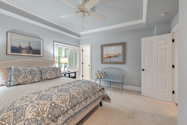 bedroom with light carpet, a tray ceiling, ornamental molding, ceiling fan, and baseboards