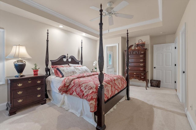 bedroom featuring light colored carpet, a tray ceiling, baseboards, crown molding, and ensuite bath
