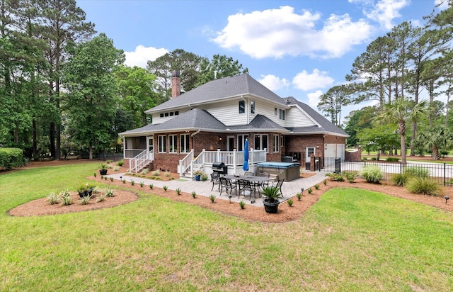 back of property with a hot tub, a patio, brick siding, a sunroom, and a chimney