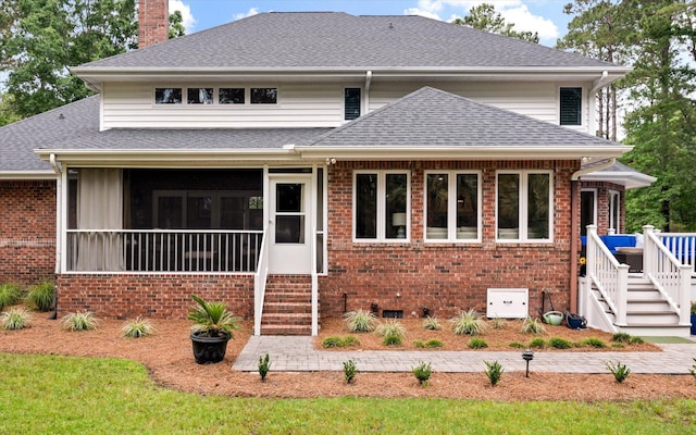 view of front of property with roof with shingles, a sunroom, a deck, a chimney, and brick siding