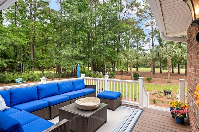 deck featuring an outdoor living space, fence, and view of wooded area