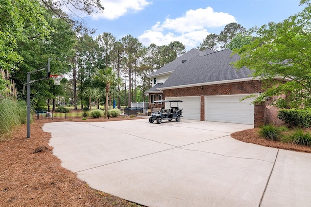 view of side of property with driveway, brick siding, a shingled roof, a garage, and fence