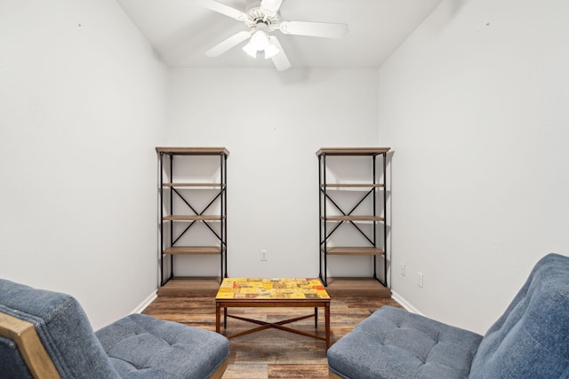 living area featuring ceiling fan and dark wood-type flooring