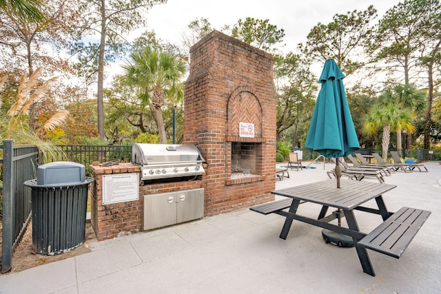 view of patio featuring area for grilling, an outdoor brick fireplace, and a grill