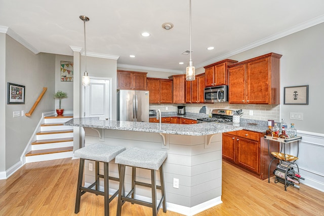 kitchen with pendant lighting, light stone counters, a center island with sink, and appliances with stainless steel finishes