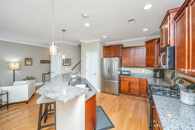 kitchen with sink, a breakfast bar area, hanging light fixtures, a kitchen island with sink, and stainless steel appliances