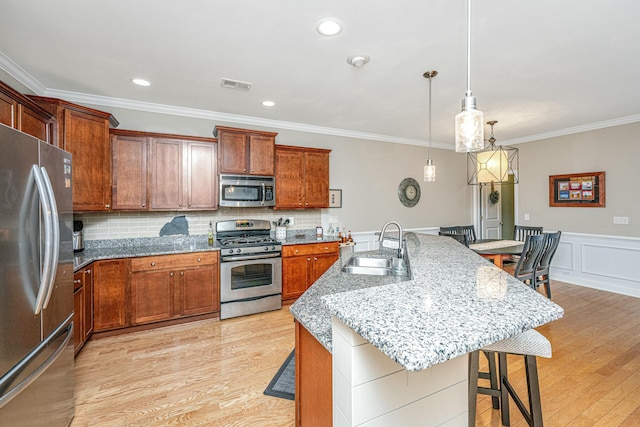 kitchen featuring sink, hanging light fixtures, a kitchen bar, stainless steel appliances, and a center island with sink