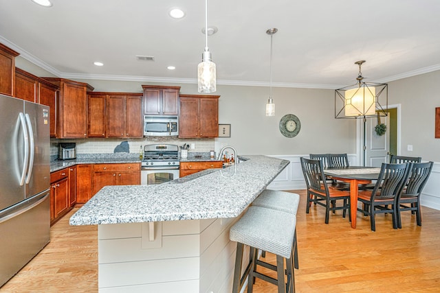 kitchen featuring pendant lighting, a center island with sink, a breakfast bar area, and appliances with stainless steel finishes