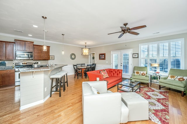 living room with sink, crown molding, ceiling fan, light hardwood / wood-style floors, and french doors