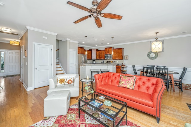 living room with crown molding, ceiling fan, sink, and light hardwood / wood-style flooring