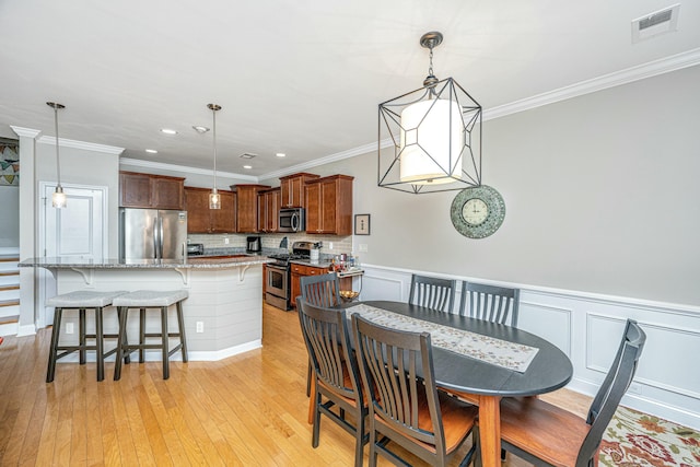 dining room featuring crown molding and light wood-type flooring