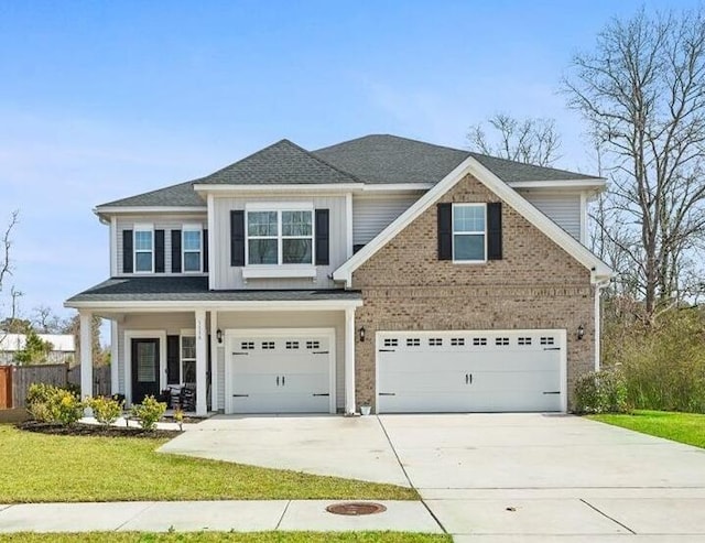 view of front of house with a front yard, driveway, a shingled roof, a garage, and brick siding