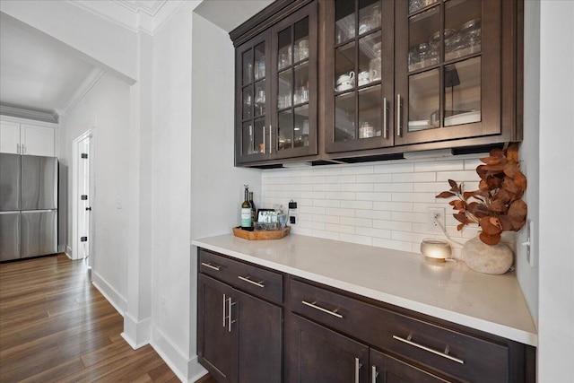 bar with tasteful backsplash, baseboards, ornamental molding, freestanding refrigerator, and dark wood-style flooring