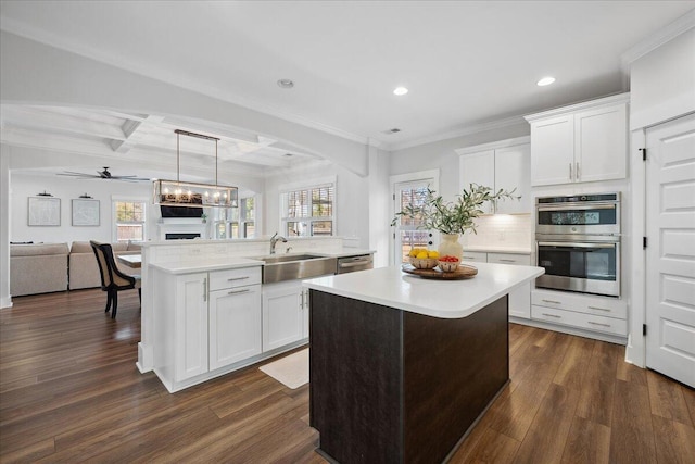 kitchen with a wealth of natural light, a kitchen island, dark wood-style floors, open floor plan, and appliances with stainless steel finishes