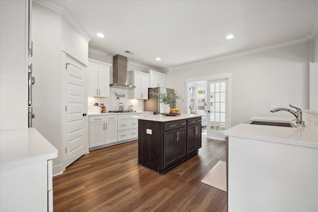 kitchen featuring a sink, tasteful backsplash, a kitchen island, dark wood-style floors, and wall chimney exhaust hood