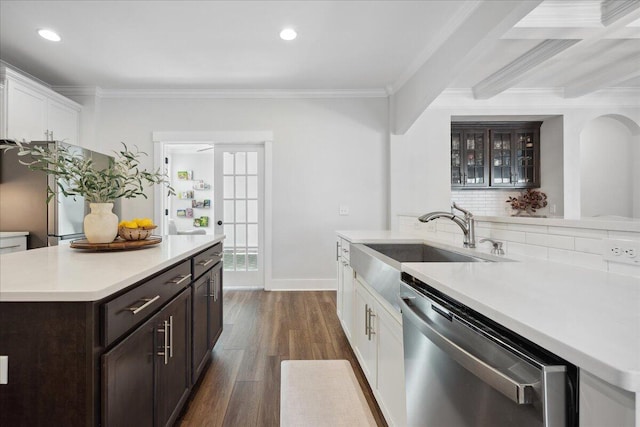 kitchen featuring a sink, ornamental molding, light countertops, appliances with stainless steel finishes, and a center island