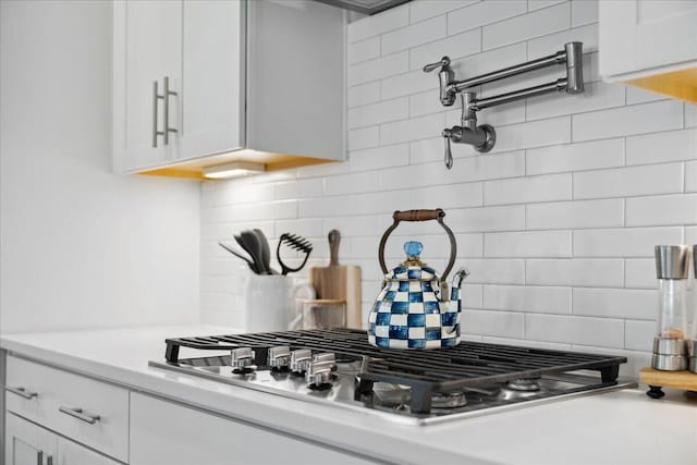 room details featuring stainless steel gas cooktop, white cabinetry, light countertops, and tasteful backsplash