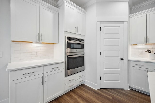 kitchen featuring double oven, light countertops, ornamental molding, white cabinetry, and dark wood-style flooring