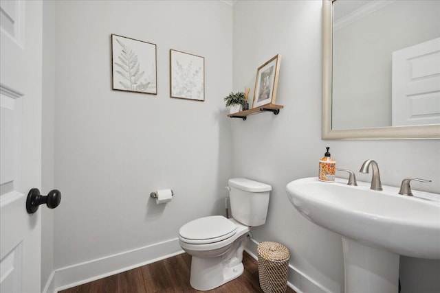 bathroom with toilet, wood finished floors, baseboards, and a sink