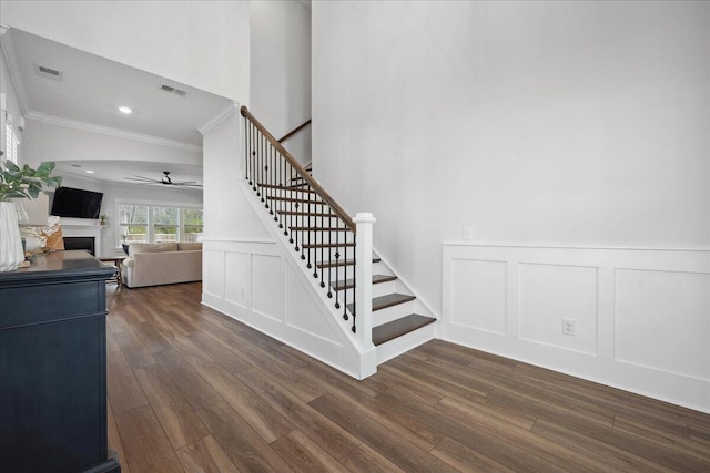 stairs featuring visible vents, a decorative wall, a ceiling fan, and wood finished floors