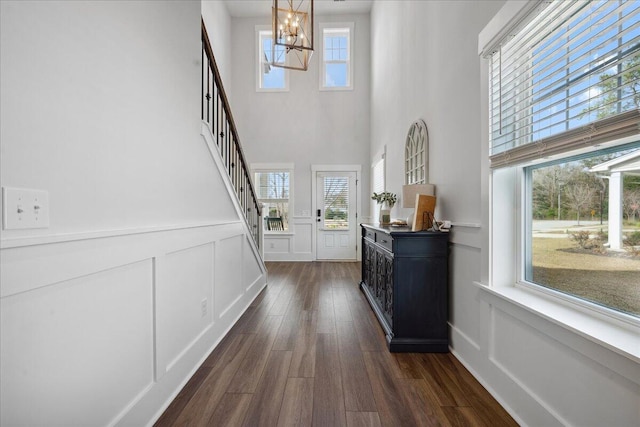 foyer entrance with a wainscoted wall, a chandelier, dark wood-style flooring, and a decorative wall